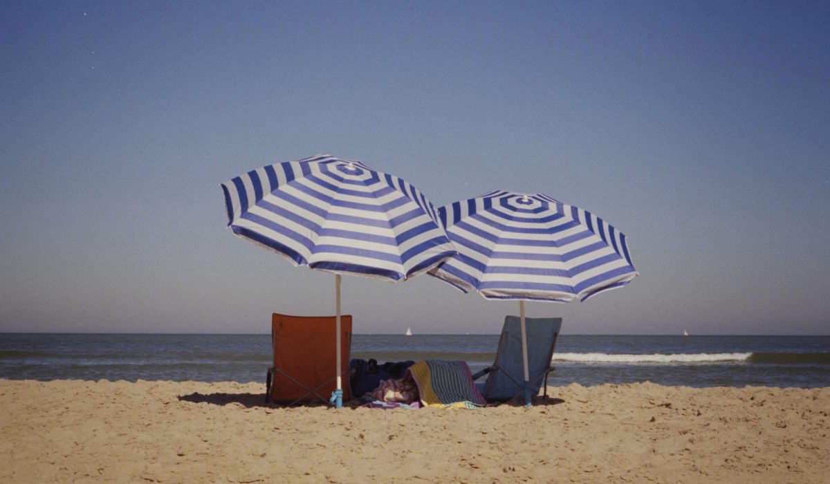a couple of umbrellas sitting on top of a sandy beach